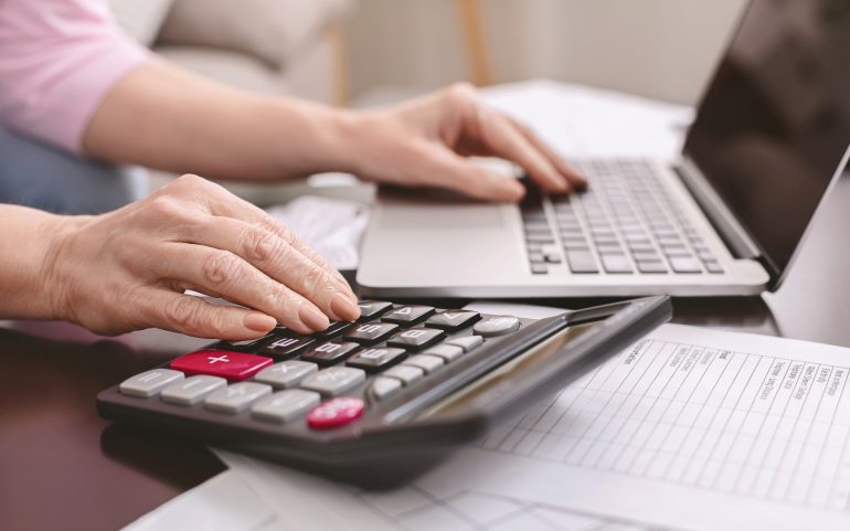 senior woman with calculator counting dollar money at home Finances : Réduction des délais de dépôt des déclarations fiscales mensuelles à partir du 1er janvier 2024